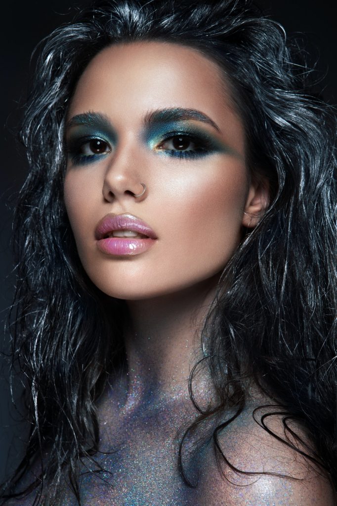 Beautyful girl with blue glitter on her face